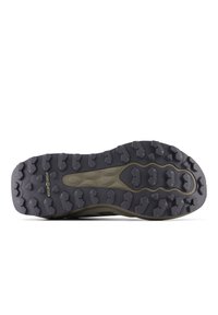 Semelle de chaussure de trail running avec une surface en caoutchouc gris foncé, présentant des motifs de雕刻 agressifs et une crête centrale pour l'adhérence.