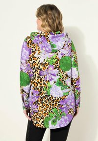 Barevná květinová a leopardí potiskovaná mikina s kapucí, s fialovými, zelenými a oranžovými vzory. Dlouhé rukávy, volný střih a kapuce.