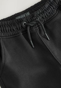 Schwarze Baumwoll-Sweatpants mit elastischem Bund, verstellbarem Kordelzug und flachen Nähten. Das Etikett lautet "REGULAR."