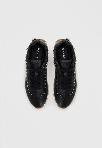 Zwarte leren sneakers met zilveren studs langs de zijkanten, ronde neus en zwarte veters. Voorzien van een tan rubberen zool en een reliëflogo.