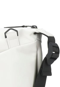 White waterproof bag with a textured finish, featuring black hardware, an adjustable strap, and a rolled top closure design.