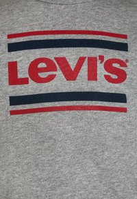 T-shirt grigio con un design a righe rosse e blu navy, caratterizzato dal nome del marchio "Levi's" in bold lettere rosse sul petto.