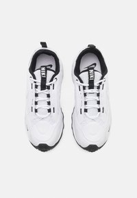 White athletic shoes with black accents, featuring a mesh tongue, lace closure, and a sturdy black rubber outsole.