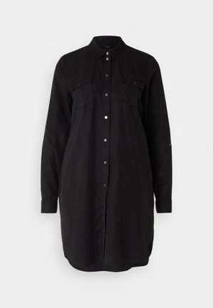 Robe chemise noire à boutons, en coton. Elle possède deux poches poitrine, des manches longues et un ourlet arrondi. Texture lisse et design classique.