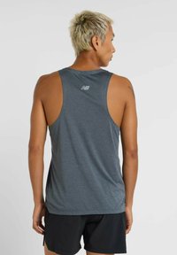 Grijze sportieve tanktop met een gestructureerde afwerking, racerbackdesign en logo-detail op de rug. Draagt met zwarte short.