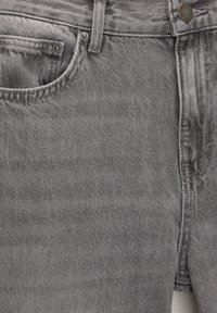 Gros plan sur un jean denim gris montrant la poche avant, la passants de ceinture, le bouton et les détails des coutures.