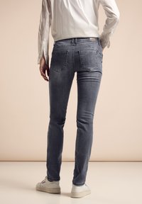 Tight grå denimjeans med en slät yta, med bakfickor och midjehöjd, kombinerat med vita sneakers.