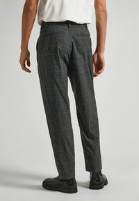 Grå mönstrade byxor i texturerat material, smal passform, med bakfickor, tillsammans med svarta ankelboots.