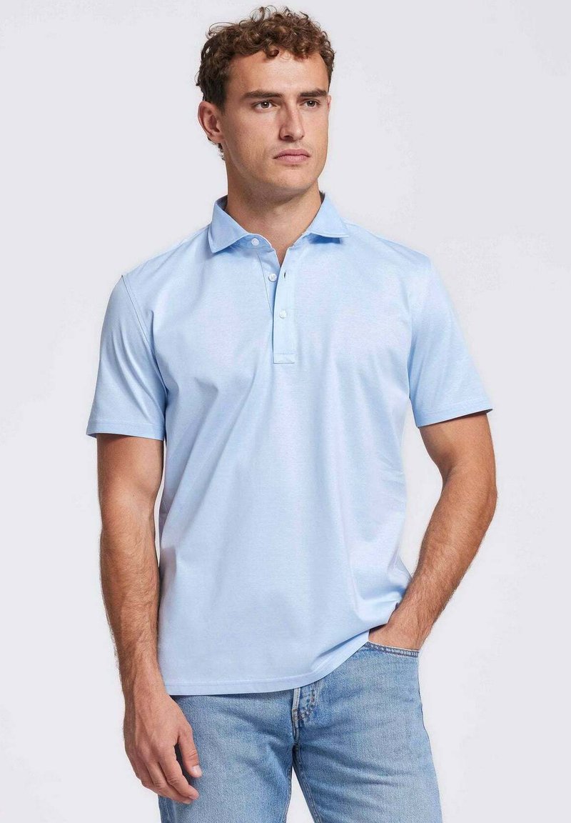 Lichtblauwe polo met een gladde stof, voorzien van een klassieke kraag, een knopenlijst met drie knopen en korte mouwen; gecombineerd met lichtblauwe denim jeans.