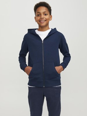 Felpa con cappuccio blu navy, in misto cotone, con tasche frontali, polsini a costine e finitura uniforme. Indossata sopra una maglietta bianca.