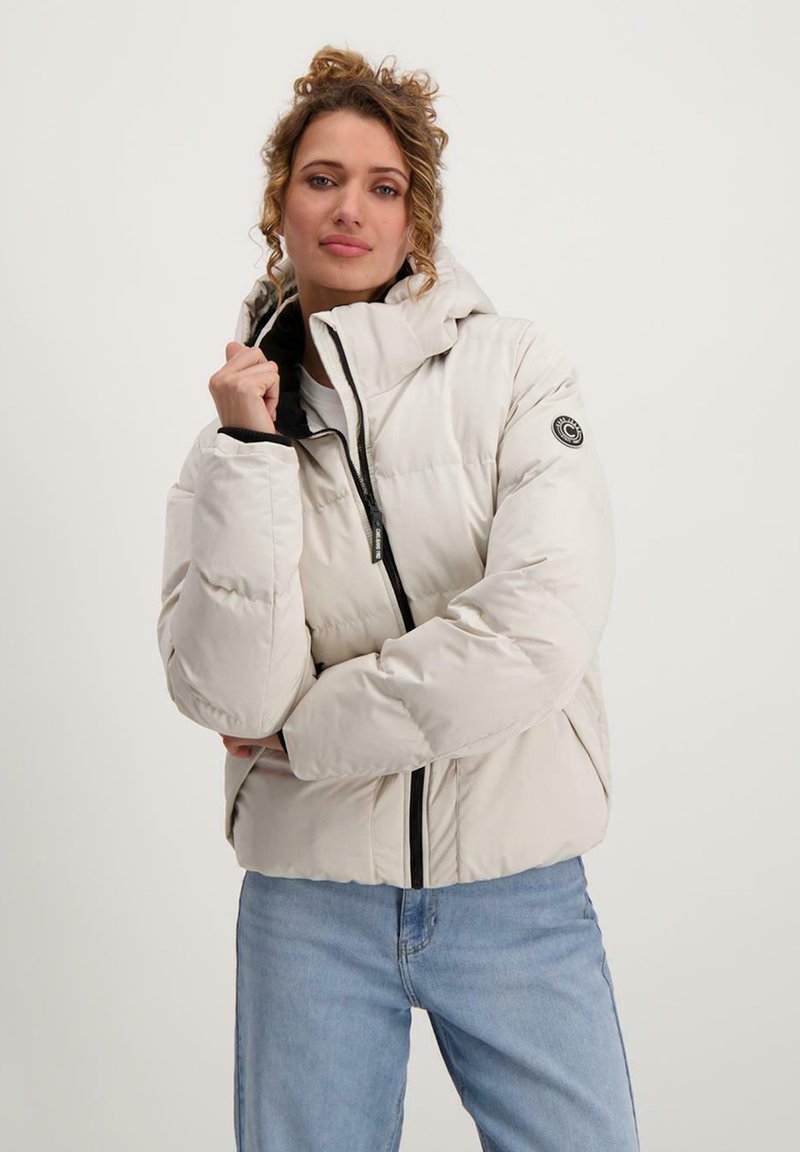 Lichtgewicht gewatteerde jas in crème met een aansluitende capuchon, zwarte rits en elastische manchetten. Bevat een rond logo op de linkermouw.