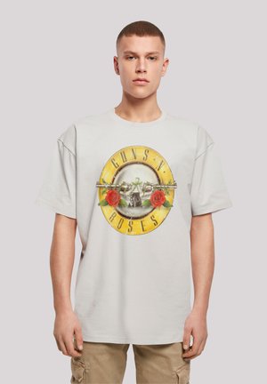 Light gray cotton t-shirt featuring a circular graphic with "GUNS N' ROSES," two red roses, barbed wire, and a skull in the center.