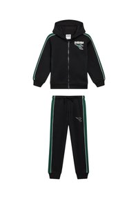 Felpa con zip nera e pantaloni abbinati con strisce laterali verdi e bianche, loghi Diadora sul petto e sulla gamba del pantalone.