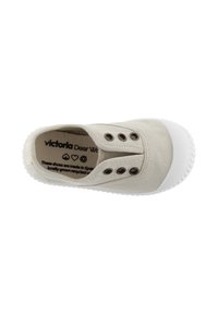 Beige canvas slip-on sko med hvid gummisål, der har metaløjer og en glat overflade. Indvendige mærker angiver brand og plejeinformation.