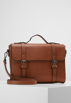 Brązowa skórzana torba na ramię z górnym uchwytem, przednią klapą zabezpieczoną dwoma paskami z klamrami oraz odczepianym paskiem na ramię, prezentowana na białej powierzchni.