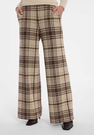 Hosen mit weitem Bein in einem beigen, braunen und cremefarbenen Karo-Muster, getragen mit dunklen spitzen Schuhen und einem beigen Rippspullover.