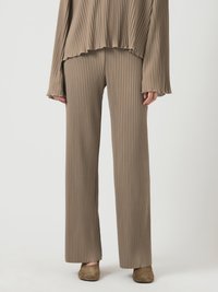Top a coste beige a maniche lunghe con pantaloni a gamba larga abbinati, caratterizzati da orli sfilacciati. Tessuto morbido con texture verticale.
