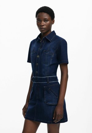 Robe chemise en denim noir à manches courtes, boutons sur le devant, deux poches poitrine, taille ceinturée et détails de surpiqûres orange contrastantes.