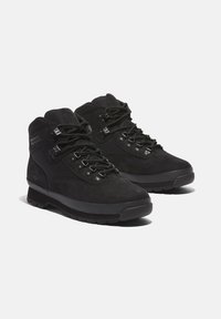 Black hiking boots with a suede and textile upper, reinforced eyelets, and a rubber sole, featuring a padded collar and textured accents.