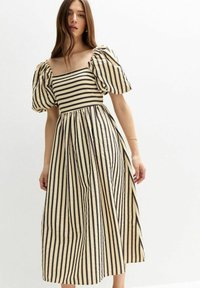 Vestido midi a rayas en beige y negro con mangas abullonadas, escote cuadrado, y una falda fluida que se recoge en la cintura. Tejido texturizado.