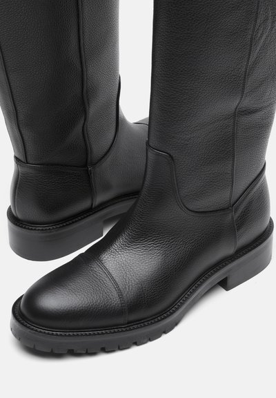 Botas de cuero negro con un acabado texturizado, punta redonda y un tacón bajo de bloque. Presentan costuras mínimas y una suela de goma resistente.
