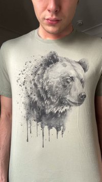 Olivegrünes T-Shirt mit einer detaillierten Schwarz- und Grauabildung eines Bären und Spritzeffekten, gefertigt aus weichem Baumwollstoff.