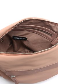 Unutrašnjost ružičaste torbice od umjetne kože sa zip džepom, glatkom tkaninom, smešnim podstavljanjem i brendiranim oznakom. Srebrni zatvarač.