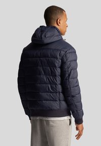 Navy puffer jacket with a hood, featuring a quilted design, ribbed cuffs, and hem, soft texture, and a slightly shiny finish.