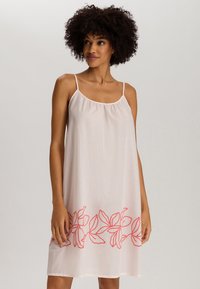 Vestido sin mangas de color rosa claro con delicadas tiras finas y diseño floral bordado en color coral en el dobladillo. Textura de tela suave y fluida.