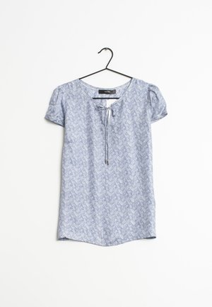 Blouse bleu clair à manches courtes avec un motif de feuilles subtil, col rond et détail de lien à l'avant, suspendue sur un cintre noir sur fond blanc.