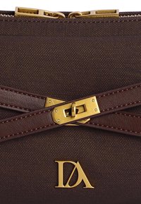 Material texturizado marrón con detalles de cuero, con cierre de candado en tono dorado y logo "DA". Parte superior con cremallera para un cierre seguro.