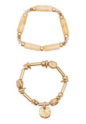 Dwie rozciągliwe bransoletki z koralikami: jedna z beżowymi prostokątnymi i okrągłymi koralikami, druga w złotym odcieniu z nieregularnymi koralikami i okrągłym wisiorkiem.
