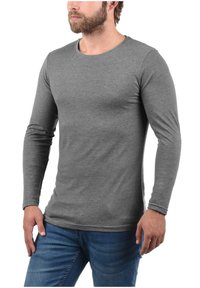 Lange mouw grijze shirt gemaakt van zacht materiaal, met een ronde halslijn en een aansluitend ontwerp, gecombineerd met een blauwe spijkerbroek.