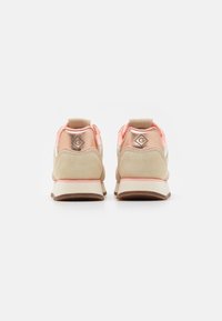 Sport shoes with a beige and pink color scheme, suede and synthetic materials, rear pull tab, and embossed logo on the heel.