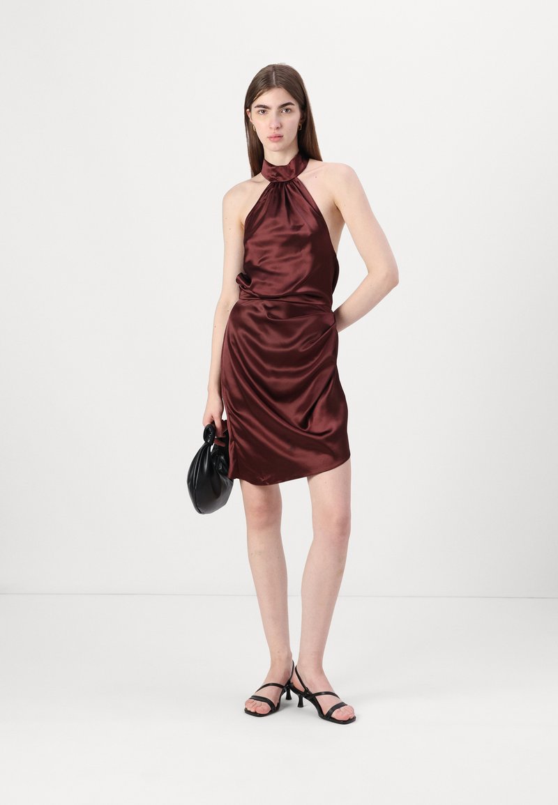 Sukienka z satyny na halter w kolorze burgundowym, z drapowaną konstrukcją i dopasowanym krojem. W połączeniu z czarnymi sandałami na paski i czarną torebką.