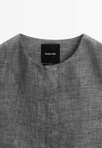 Chemise en tissu gris texturé avec encolure arrondie et étiquette noire portant la mention "Massimo Dutti" au col.
