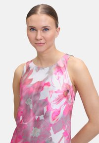 Ärmelloses Blumenshirt mit einem Muster in Pink und Grau, hergestellt aus leichtem Stoff mit einer glatten Textur.