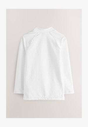 Bílá košile s dlouhými rukávy, vysokým límcem a raglánovými rukávy. Hladká textura s čistým provedením a jednoduchým designem.
