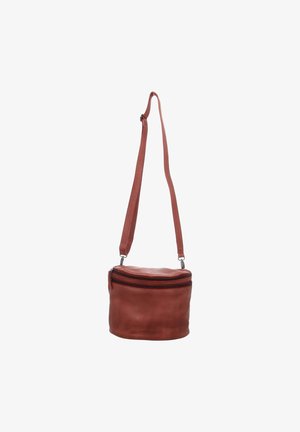 Round brown leather crossbody bag with adjustable strap and top zipper closure against white background.