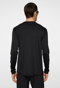 Långärmad svart sporttröja i ett slätt, stretchigt material, med rund hals och sömlös design med en slim fit.