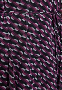 Tissu de robe avec un motif géométrique diagonal noir, violet et blanc, doté d'un devant à boutons et d'une ceinture nouée à la taille.