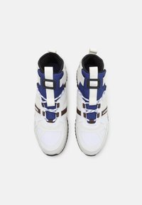 Sneakers typu high-top z połączeniem białych, niebieskich i brązowych materiałów. Akcenty z teksturowanej tkaniny oraz czarne wykończenie z regulowanymi paskami.