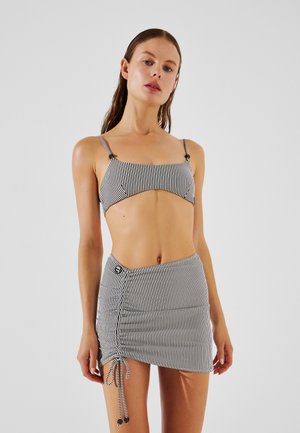 Czarny i biały kostium bikini w paski z regulowanymi ramiączkami oraz dopasowaną mini spódniczką z bocznym sznurkiem ściągającym i detalem w postaci guzika.