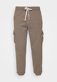 Brown sweatpants with side cargo pockets, elastic waistband, and drawstring. Made of soft material with a smooth texture.