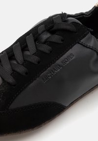 Sneaker nera caratterizzata da una combinazione di pelle liscia e camoscio. Presenta lacci, un logo sobrio in rilievo sul lato e una suola testurizzata.