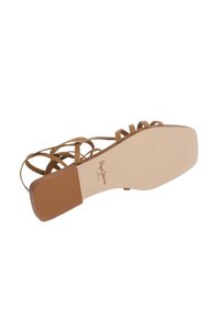 Låg sandal i tanfärgat mocka med flera korsande remmar, fyrkantig tå och texturerad brun yttersula. Märkeslogga synlig på innersulan.