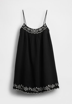 Čierne slnečné šaty s nastaviteľnými tenkými ramienkami, zdobené bielou kvetinovou výšivkou a s vlnitým lemom pozdĺž spodného okraja. Textúrovaná látka.