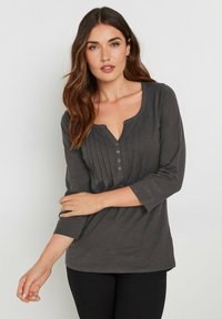 Donkergrijze longsleeve top met een diepe V-hals, knoopsluiting en geplooid voorpand. Zachte textuur en een ontspannen pasvorm.