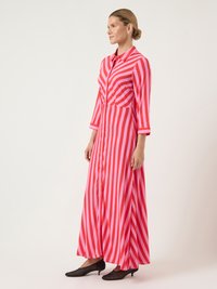 Ροζ και κόκκινο ριγέ μακρύ φόρεμα με κουμπάκια μπροστά, γιακά και τρία τέταρτα μανίκια, συνδυασμένο με μαύρες χαμηλές γόβες.