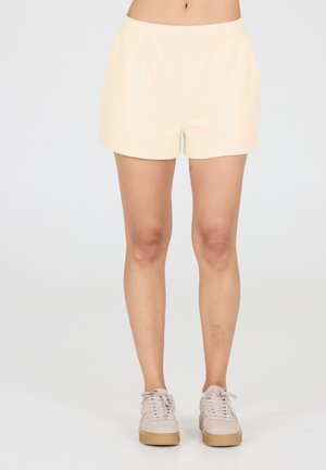 Helle beige Pull-On-Shorts mit lockerer Passform, aus glätterem Material hergestellt. Mit elastischem Bund und einem schlichten Design, getragen mit beigen Sneakers.
